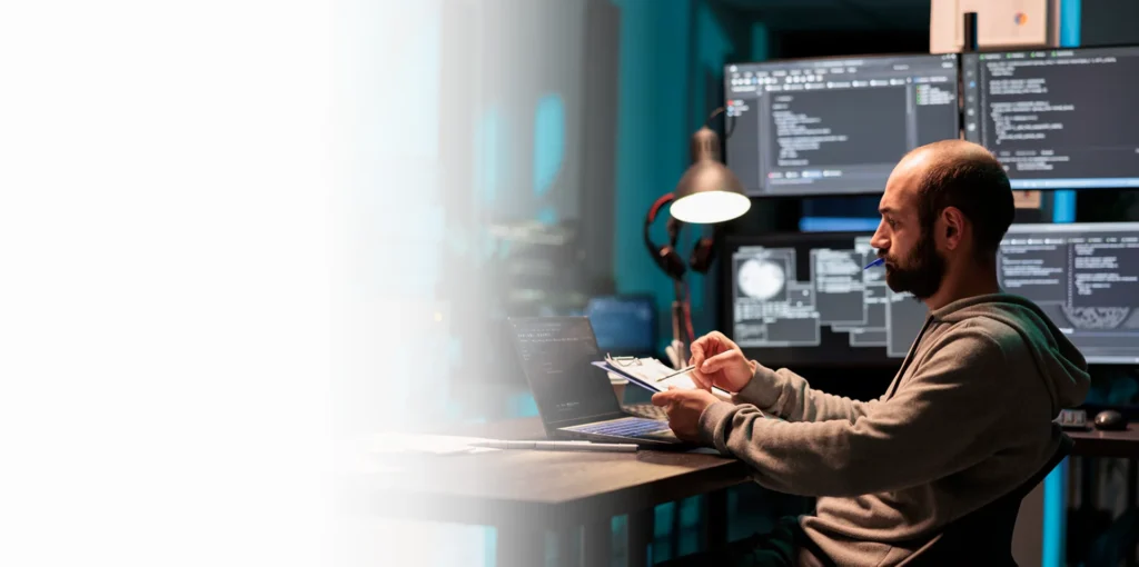 Security engineer working at multiple monitors at night, cybersecurity services Los Angeles