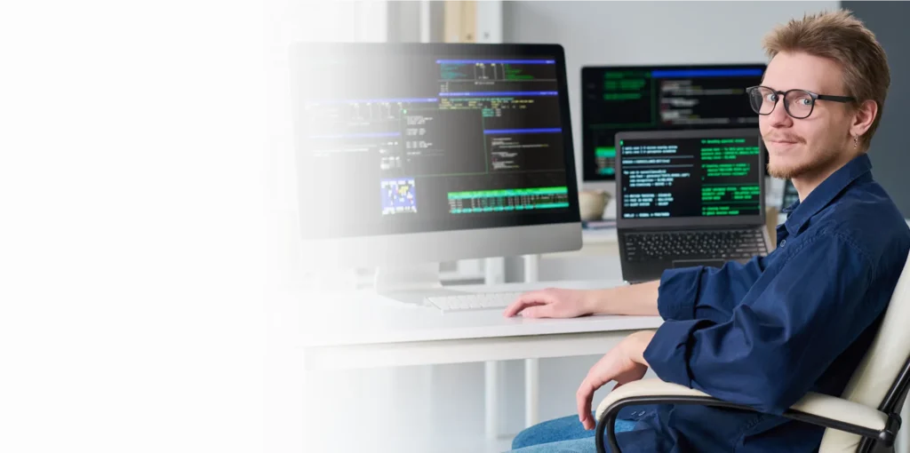 IT specialist with glasses at monitors showing code, cybersecurity services in New York