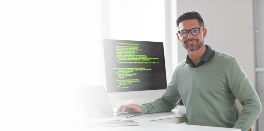 IT professional at a desk with a monitor showing code, managed cybersecurity services
