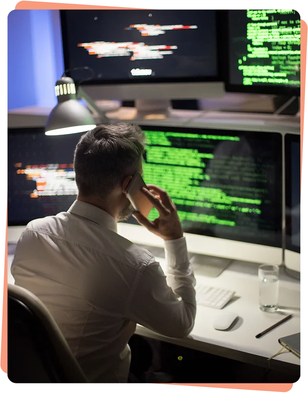 Security analyst on a phone call while monitoring code on screens, cybersecurity services Phoenix