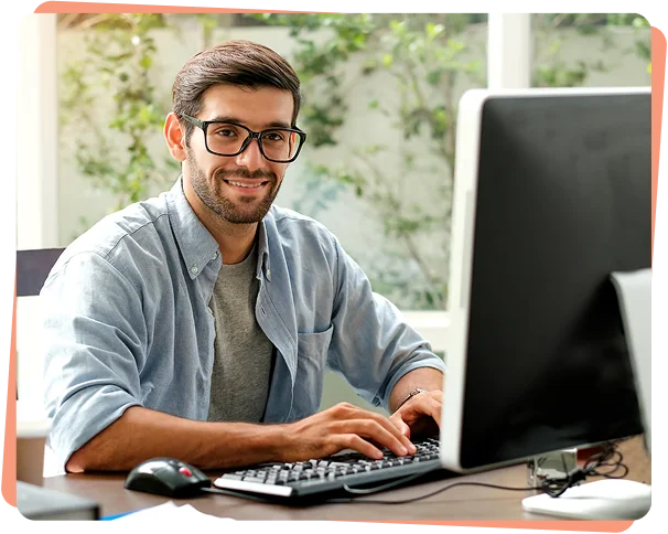 Smiling IT professional with glasses typing at a desktop computer, cybersecurity services Austin