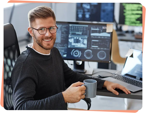 Smiling security analyst with coffee at a multi-monitor workstation, cybersecurity services LA