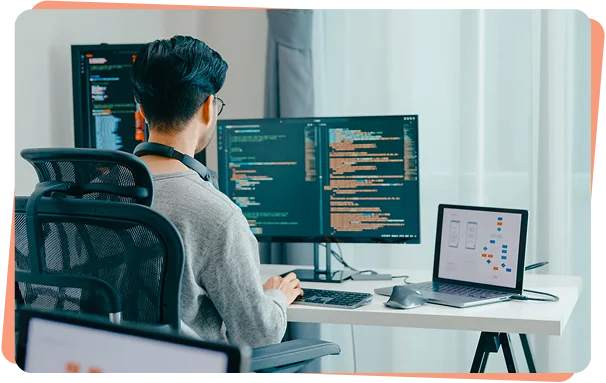 Developer reviewing code on two monitors at a desk, cybersecurity services Charlotte