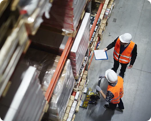 Warehouse workers in hard hats checking inventory between racks, cybersecurity for logistics