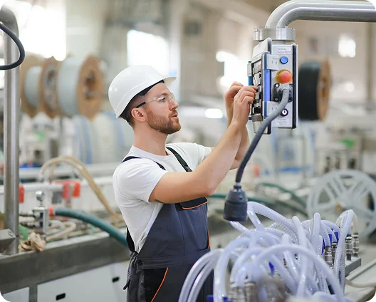 Factory technician in a hard hat operating industrial equipment, cybersecurity for manufacturers