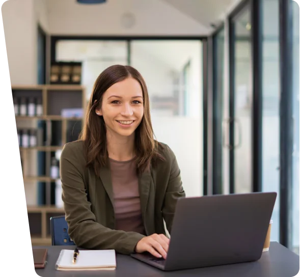Smiling woman working on a laptop at an office desk, cybersecurity services Phoenix