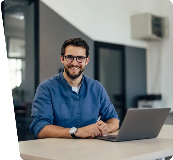 Smiling business owner with glasses at a laptop, cybersecurity services in Austin