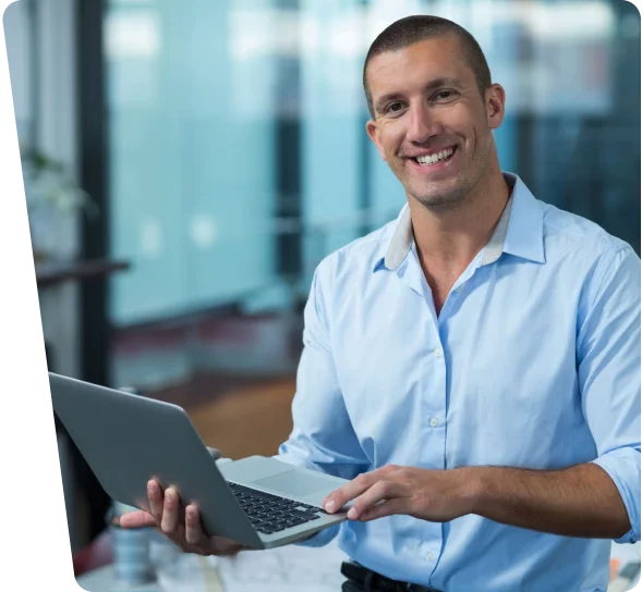 Smiling IT professional holding a laptop in an office, cybersecurity services in Los Angeles