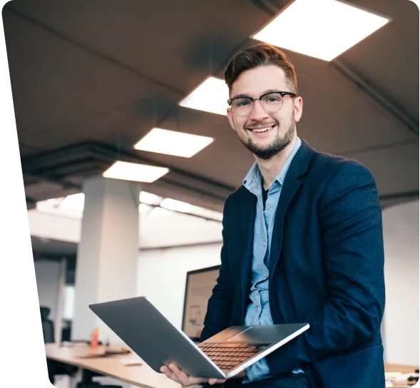 Smiling IT professional holding a laptop in an office, cybersecurity services Cincinnati