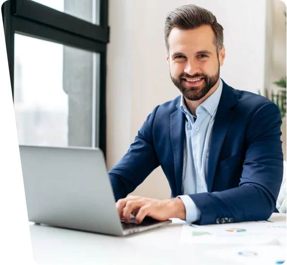 Smiling businessman in a navy suit working on a laptop, cybersecurity services Atlanta
