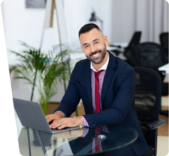 Smiling businessman in a suit working on a laptop, cybersecurity services Lafayette