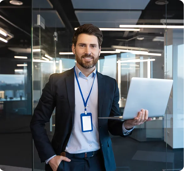 Smiling IT manager with an ID badge holding a laptop, cybersecurity services Denver