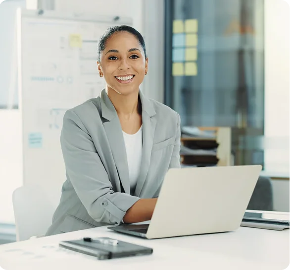 Smiling businesswoman working on a laptop at a desk, cybersecurity services in Minneapolis