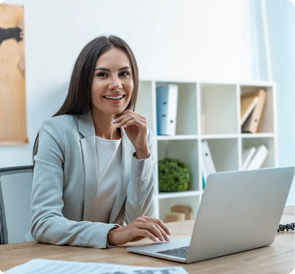 Smiling businesswoman working on a laptop in an office, cybersecurity services NYC
