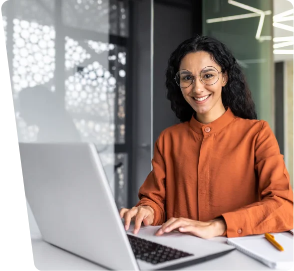 Smiling woman with glasses working on a laptop, cybersecurity services Atlanta