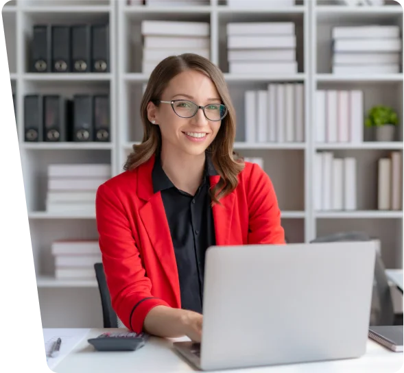 Smiling woman in a red blazer working on a laptop, cybersecurity services NYC