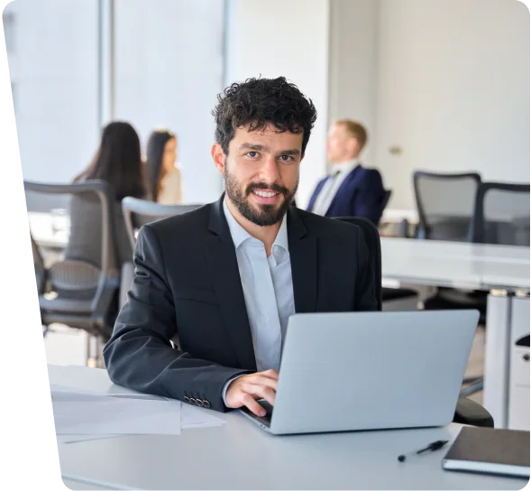 Smiling businessman working on a laptop in an open office, cybersecurity services Denver