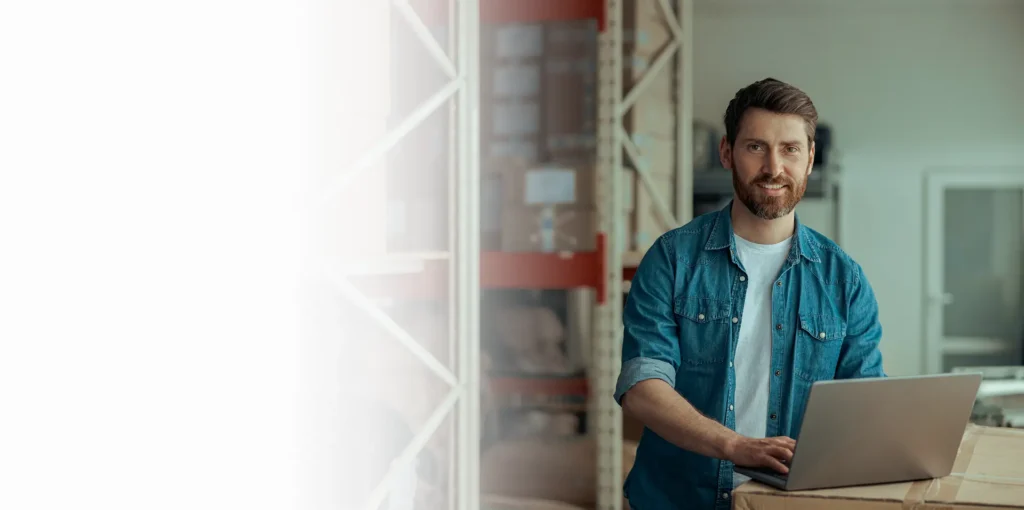 Logistics worker using a laptop in a warehouse for shipping cybersecurity