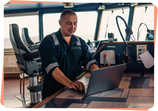 Ship officer using a laptop on a vessel bridge to monitor maritime cybersecurity