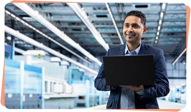 Engineer holding a laptop on a factory floor, industrial cybersecurity for OT and ICS environments