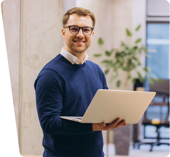 Smiling engineer with glasses holding a laptop, industrial cybersecurity services for OT and ICS
