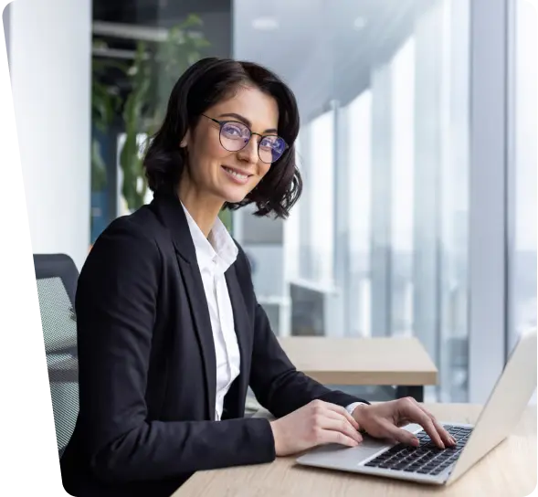 Smiling businesswoman with glasses typing on a laptop, shipping cybersecurity services