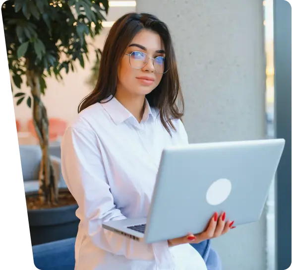Smiling woman with glasses holding a laptop, shipping cybersecurity services