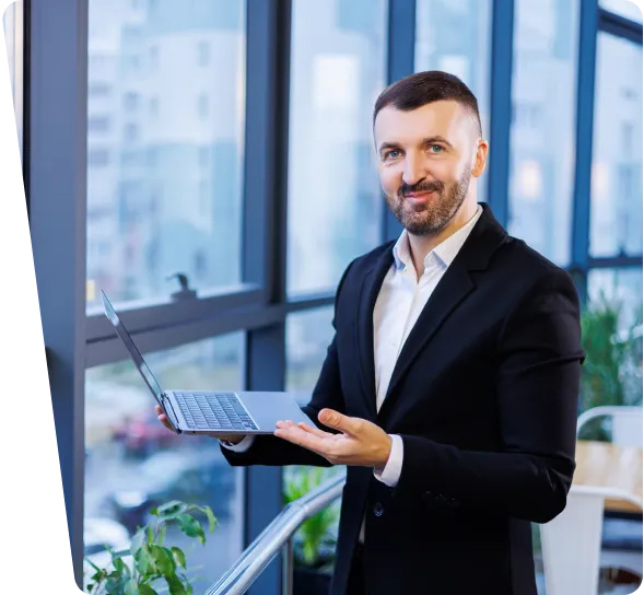 Maritime cybersecurity consultant smiling and holding a laptop beside an office window