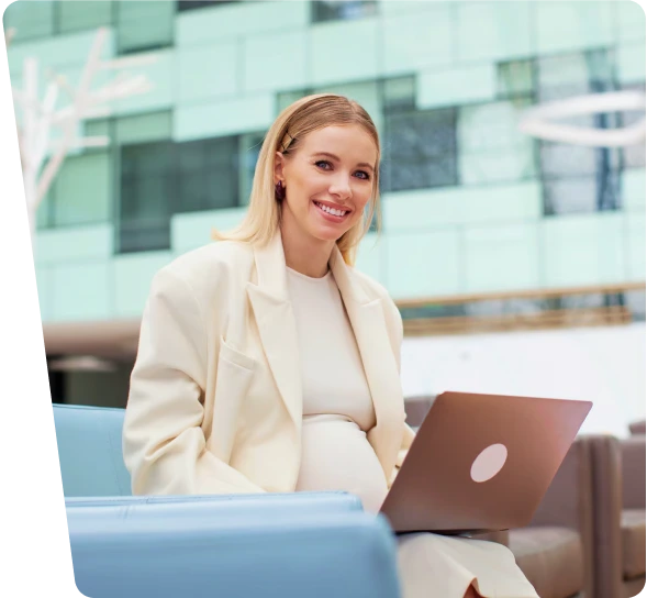 Smiling businesswoman working on a laptop in an office lounge, OT cybersecurity services