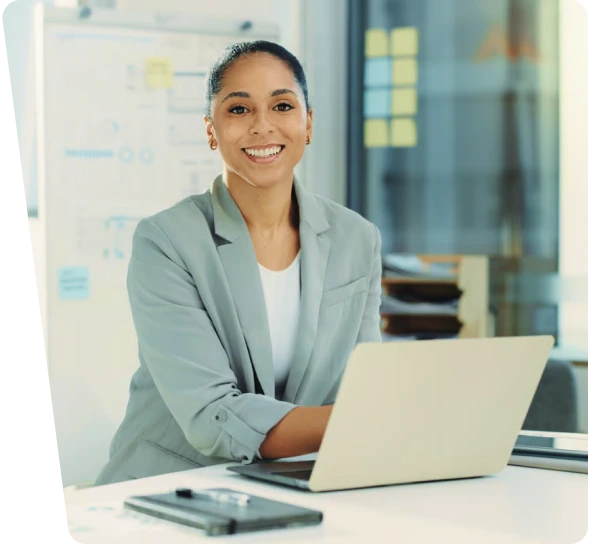 Smiling businesswoman at a laptop in an office, industrial cybersecurity services