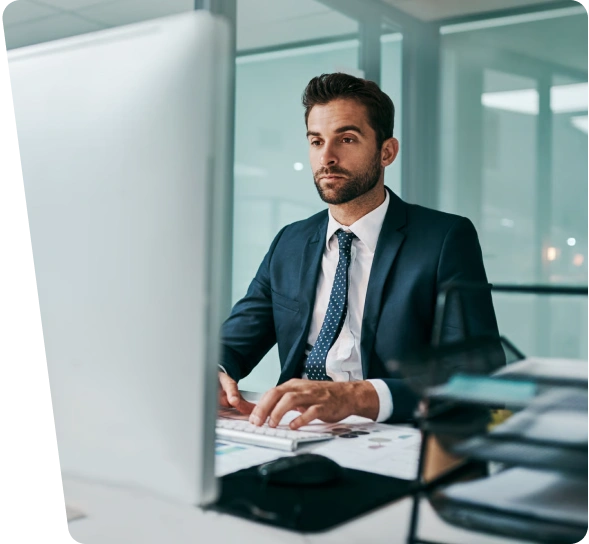 Professional in a suit working at a desktop computer, managing maritime cybersecurity services